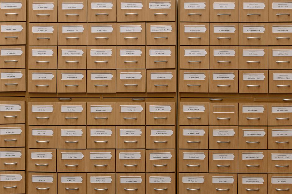 Close-up of a bank of labelled wooden storage drawers, each with a small card holder on the front.