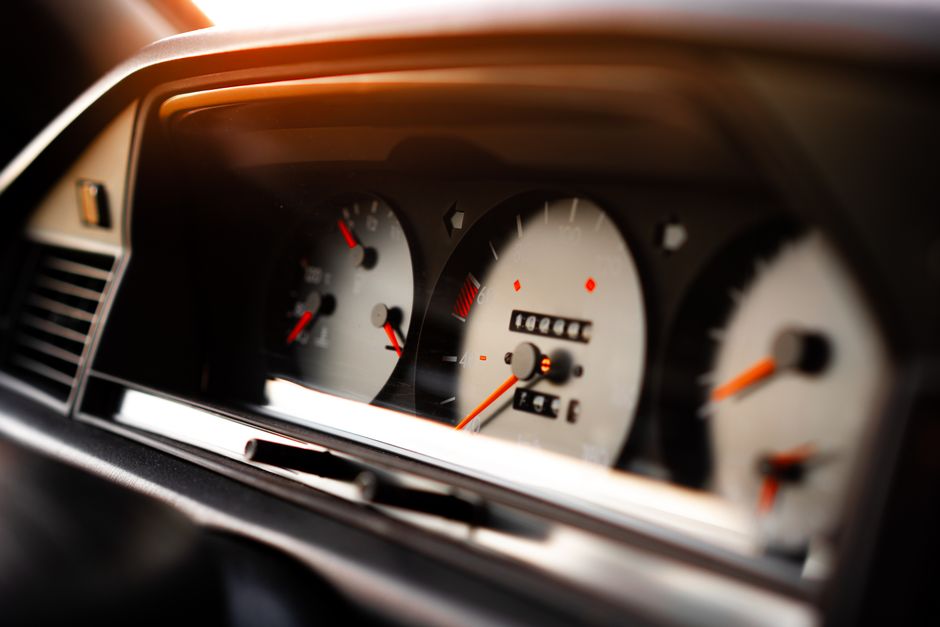 A close-up of a car instrument cluster at night, with the speedometer and the rev counter lit side by side behind the steering wheel.