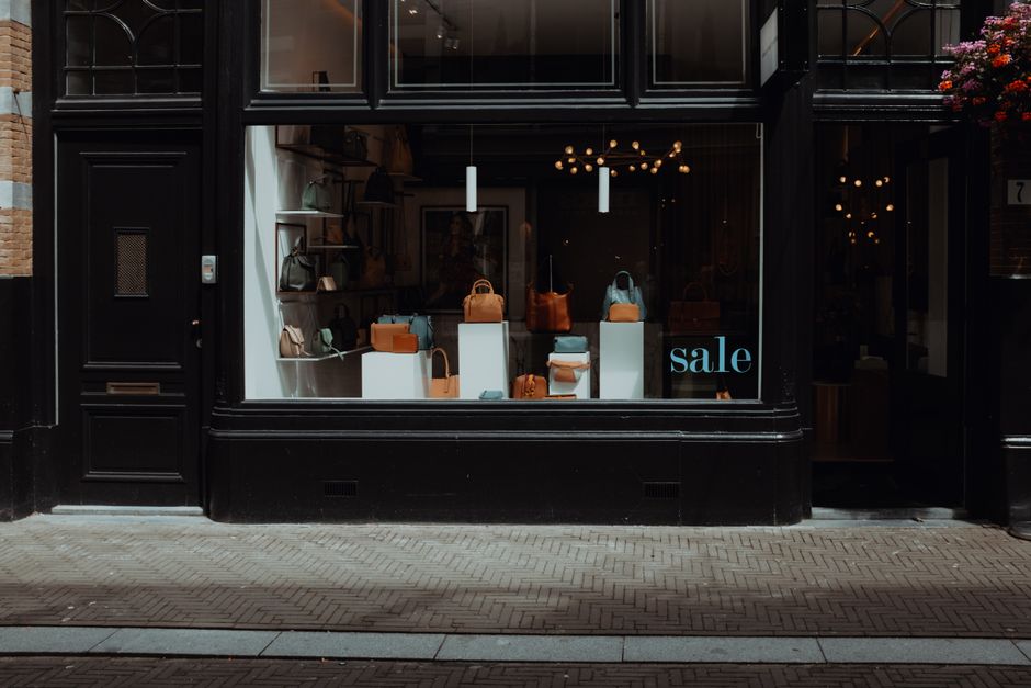 A boutique shopfront at night with handbags arranged on shelves behind a lit window.