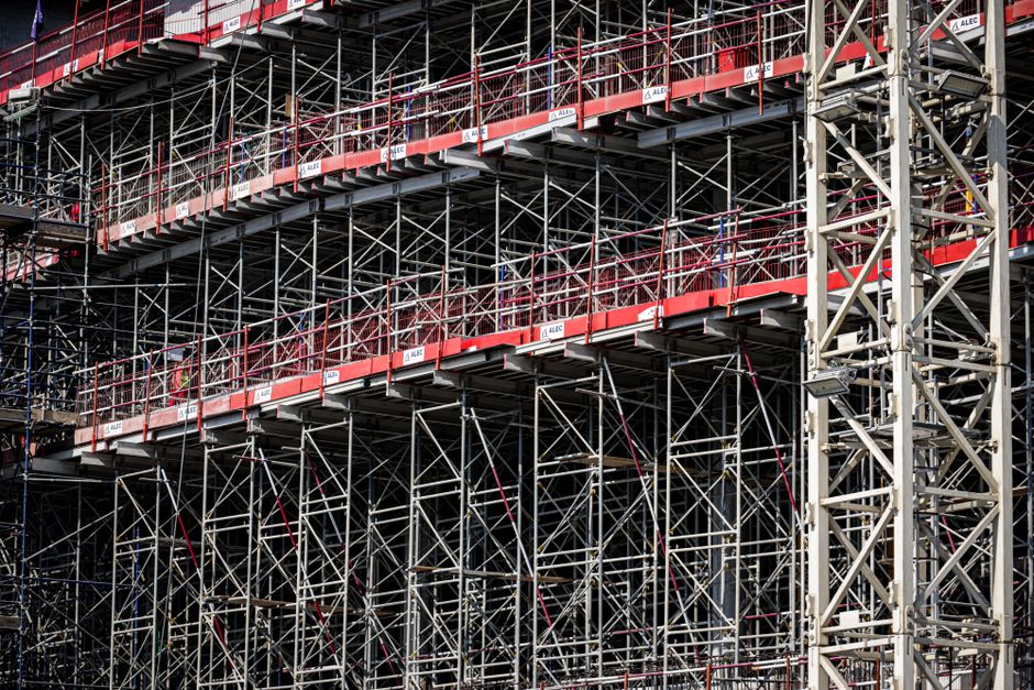 A close view of steel scaffolding poles and boards standing against a building under construction.