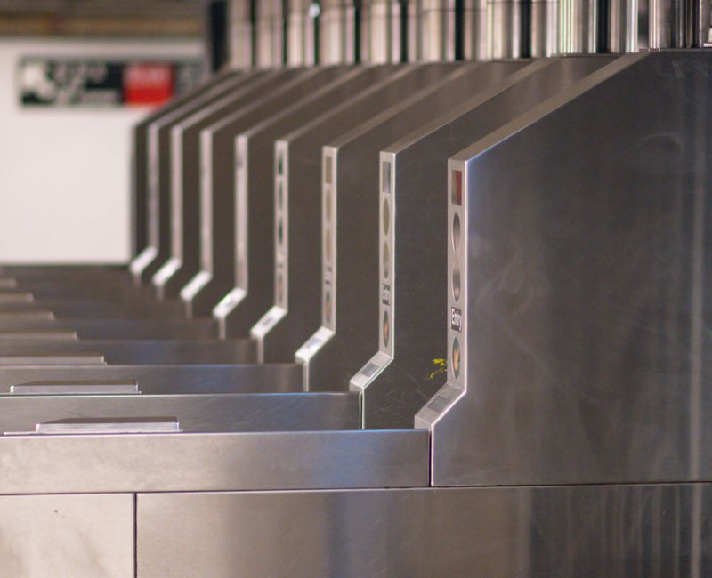 A close view of several grey subway ticket barriers in a station entrance, their gates closed, photographed straight on.