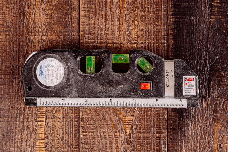 Close-up of a multipurpose laser level tool resting on a wooden table surface.